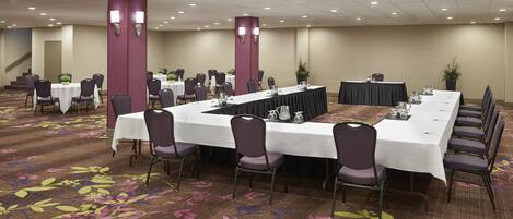 Un salón de conferencias con una mesa larga, sillas y piso alfombrado.