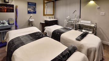 Two beds with patterned bedspreads, a bedside table, and a large mirror.