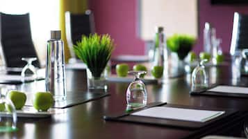 Una mesa de conferencias con botellas de agua, un bolígrafo y manzanas verdes.