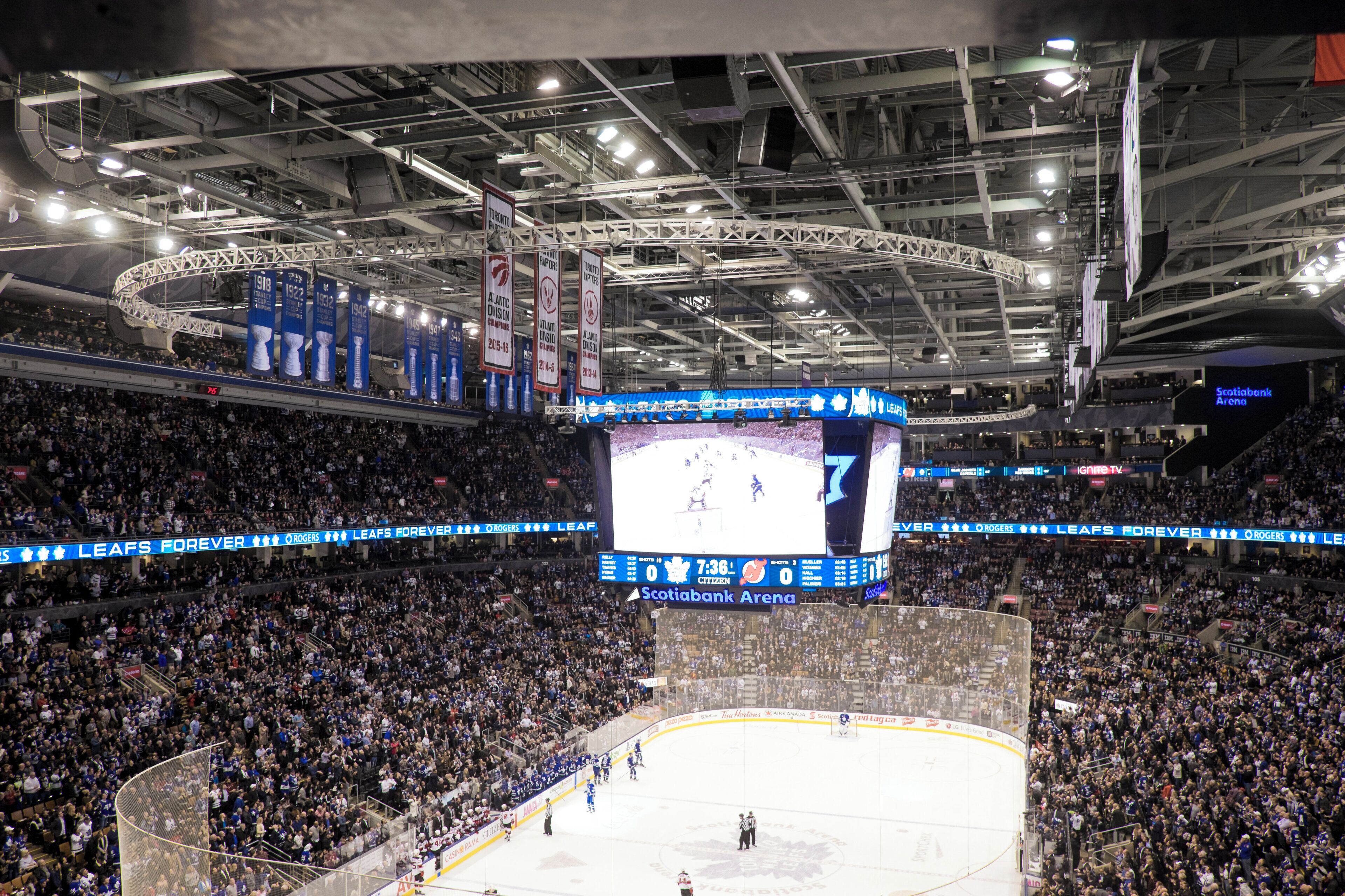 Een overdekte ijshockey arena met een groot publiek, een scorebord en een ijshockeybaan.