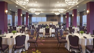 Une salle de conférence dotée de plusieurs tables et chaises, de grandes fenêtres offrant une vue sur la ville et d’un éclairage moderne.
