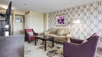 A modern living room with a sofa, armchairs, a coffee table, and a TV.
