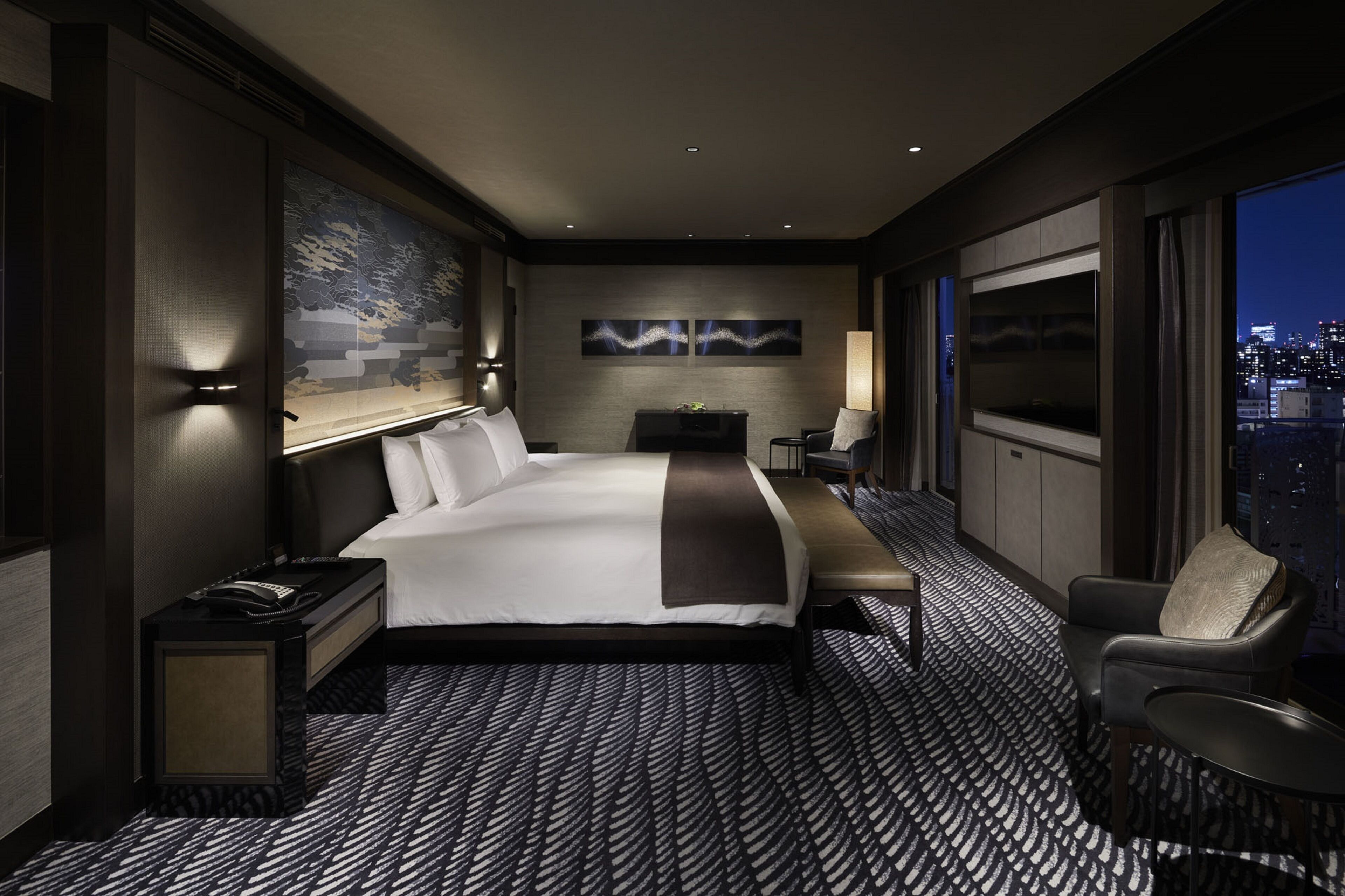 Een moderne hotelkamer met een groot bed, een bureau, een stoel en uitzicht op de stad door het raam.