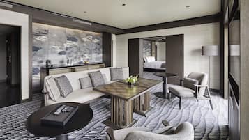 A modern hotel lobby with a sofa, armchairs, a coffee table, and a large decorative wall.