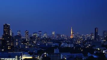 Un horizonte urbano al anochecer con edificios iluminados y una torre destacada en el centro.