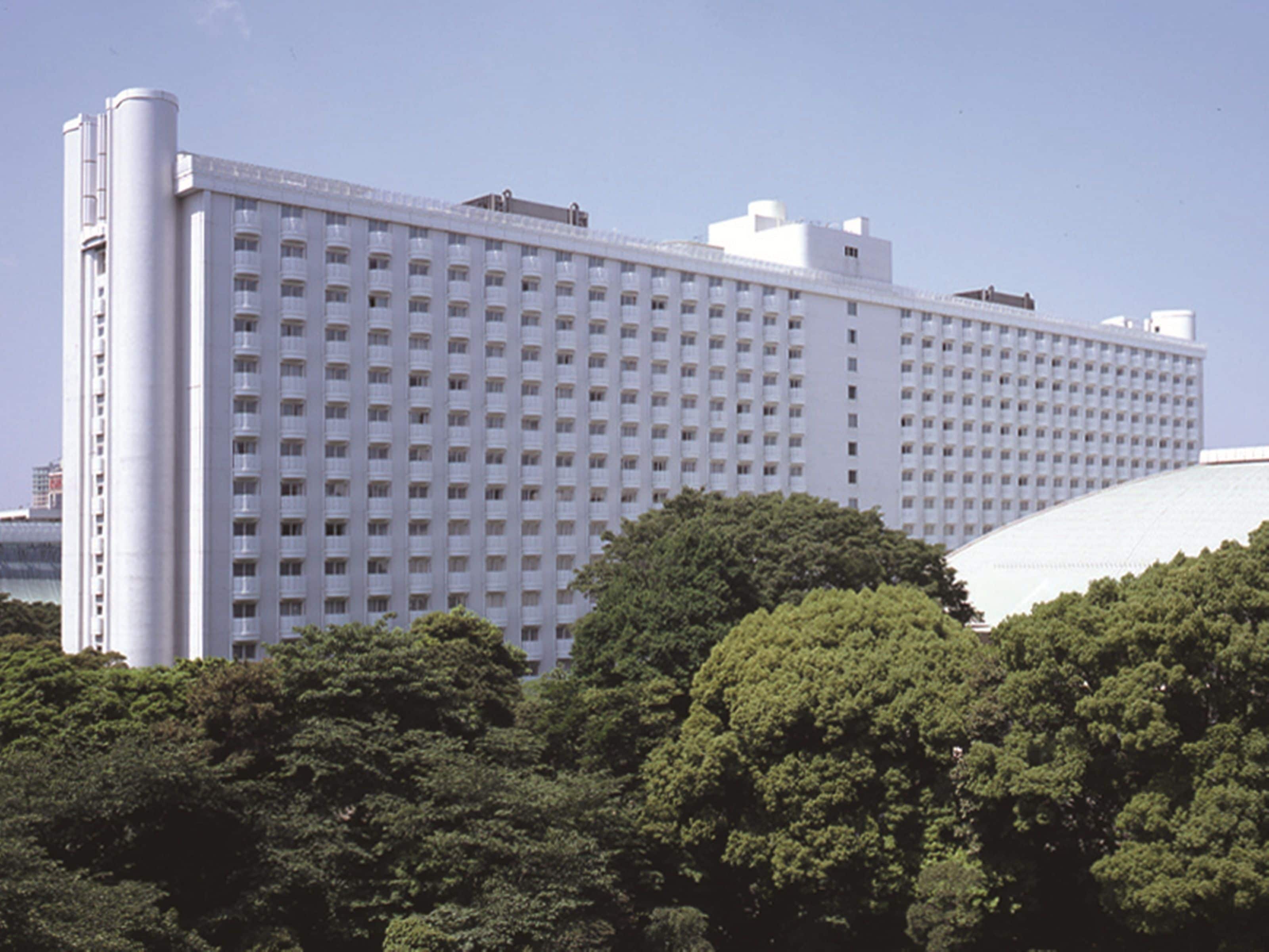 A large, modern hotel with a grid of windows and a prominent cylindrical structure on the left.