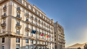 A multi-story hotel with a classical facade, balconies, and flags. - Grand Hotel Santa Lucia (Naples)