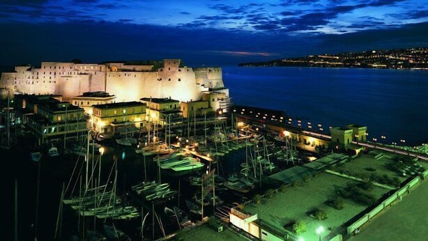 A historic fortified building with a moat, surrounded by a marina with boats. - Grand Hotel Santa Lucia (Naples)