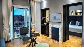 A modern hotel room with a balcony, a marble fireplace, and a framed logo on the wall. - Grand Hotel Santa Lucia (Naples)