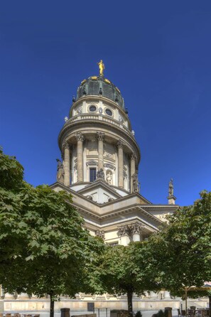 Un edificio maestoso con una cupola imponente e colonne, circondato da alberi.