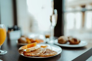 Impostazione colazione con pancake, croissant e succo d'arancia su un tavolo.