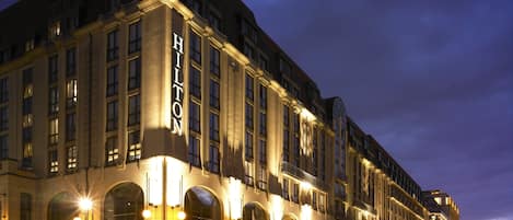 Un hotel grande e histórico con varias plantas, señalización llamativa y una fachada bien iluminada.