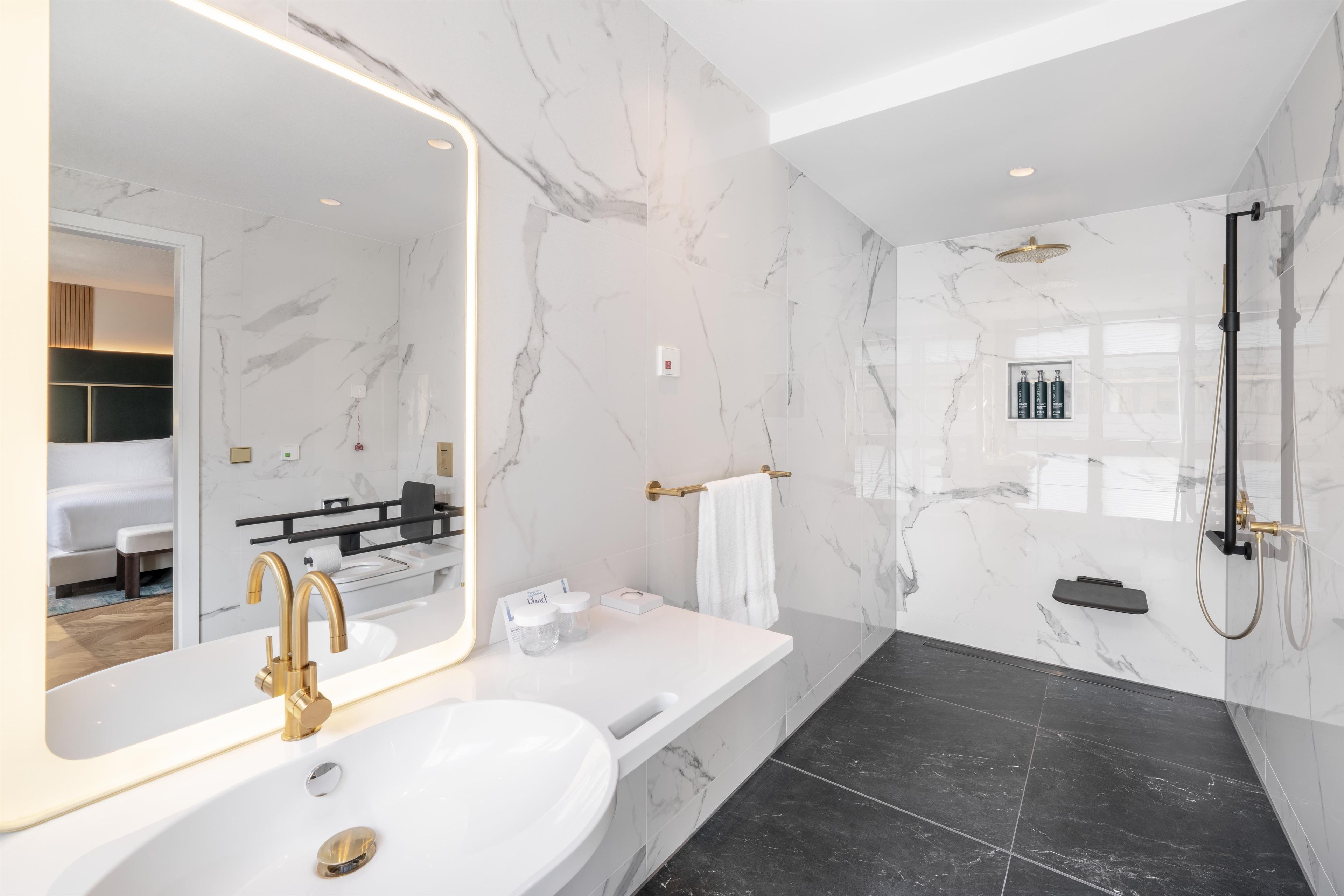 Un baño moderno con un espejo grande, una bañera, una ducha y un inodoro.