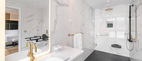 Un baño moderno con un espejo grande, una bañera, una ducha y un inodoro.