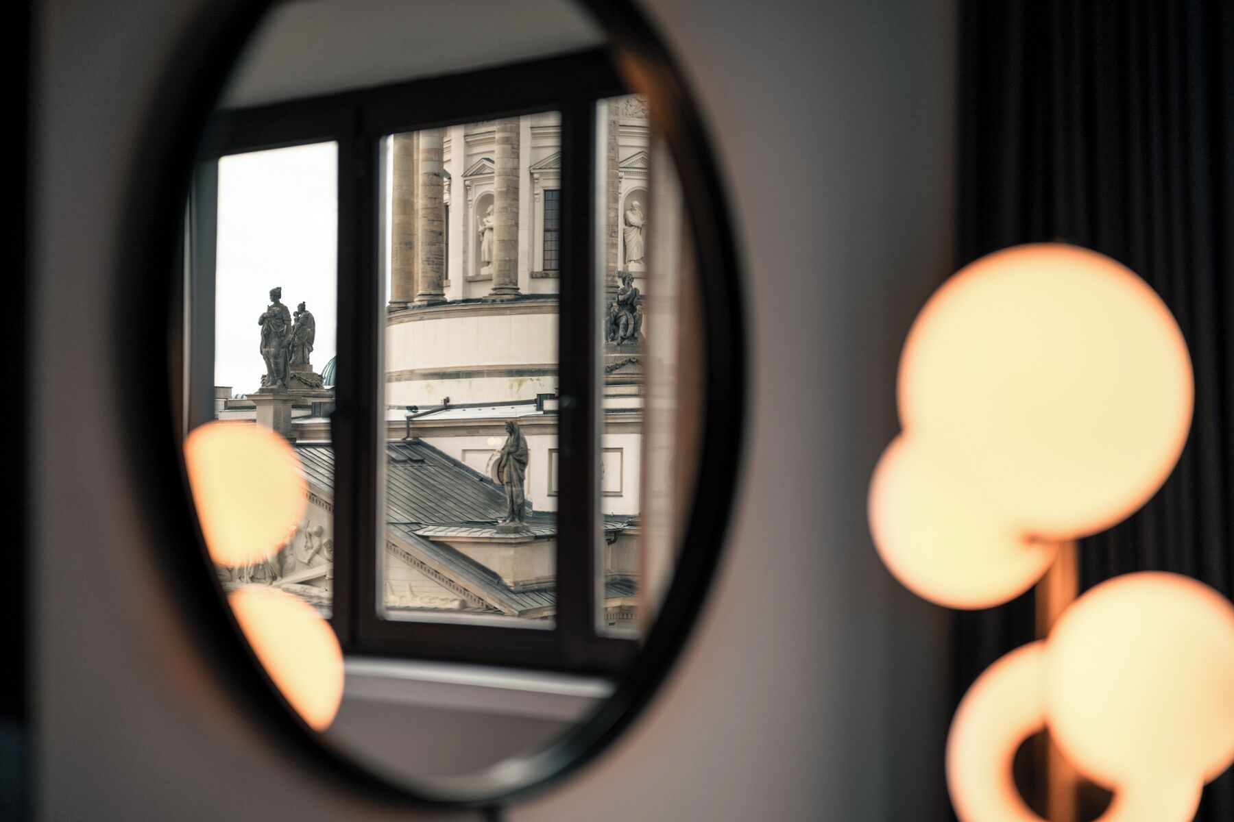 A view through a window with a statue and classical architecture.