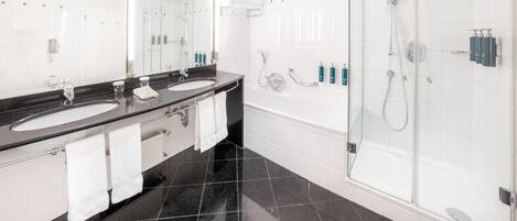 A modern bathroom with two sinks, a large mirror, and a glass-enclosed shower.