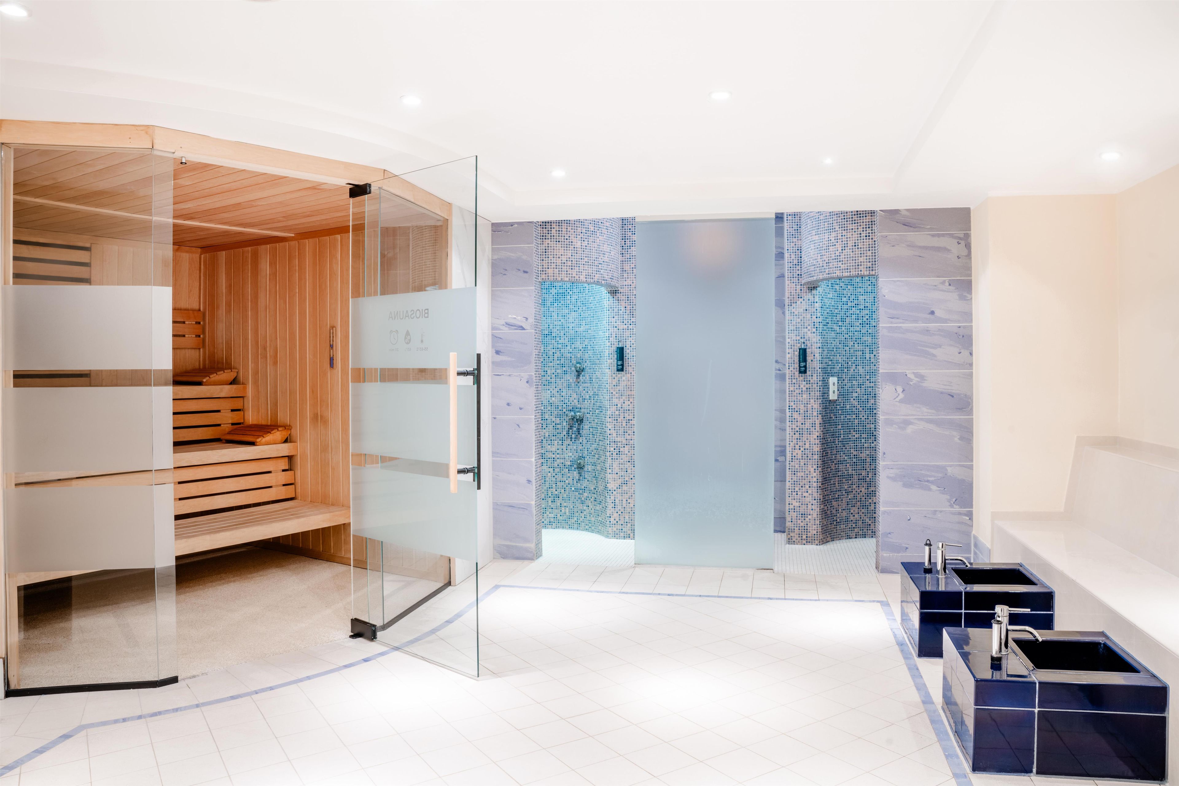 Ein modernes Badezimmer mit Glastrennwand, einer Holzzimmer und einer Mosaikwand.