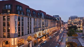 Un hotel de varios pisos con un llamativo letrero 'Hilton', que presenta un estilo arquitectónico clásico con ventanas arqueadas y una cúpula central.