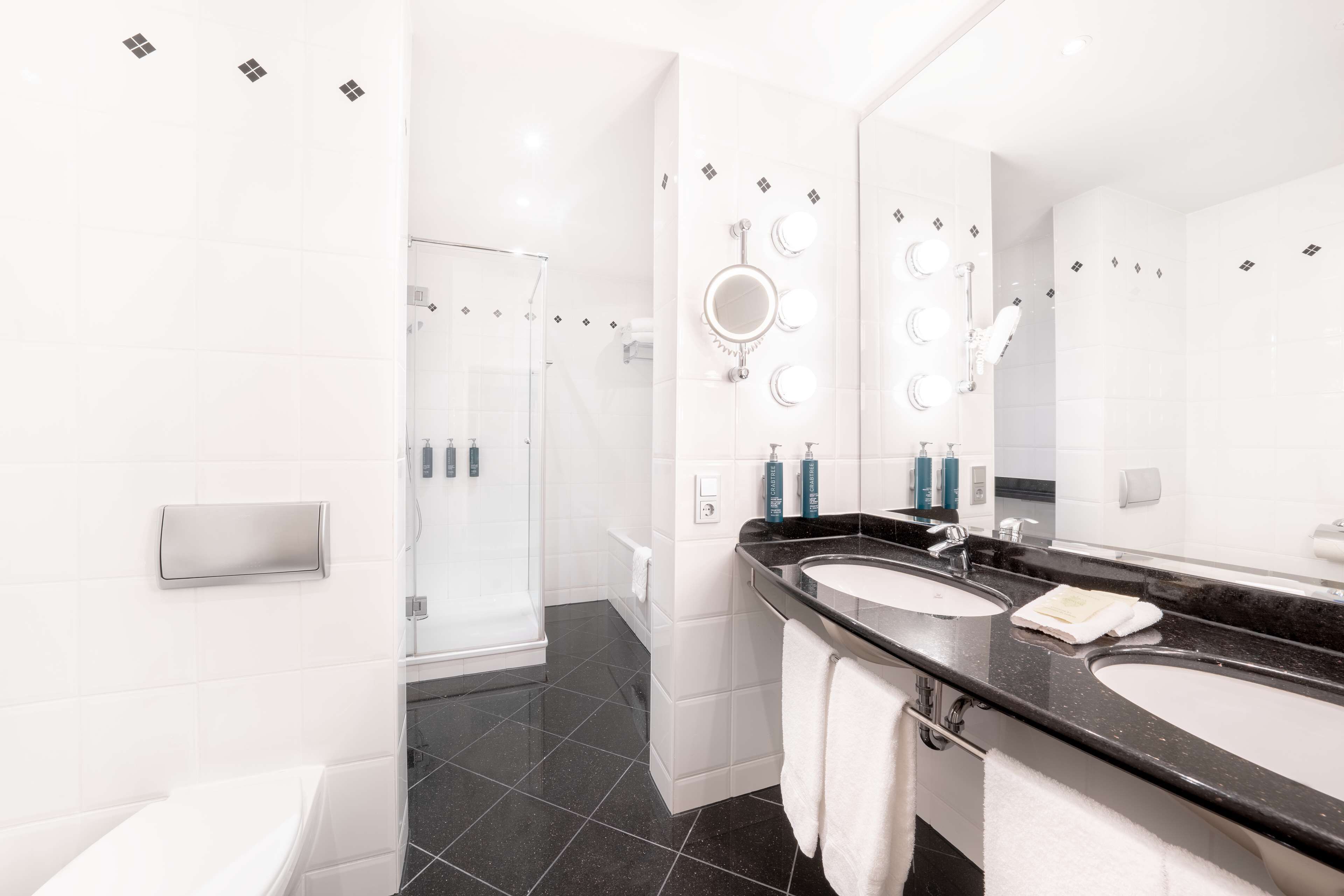 Ein modernes Badezimmer mit zwei Waschbecken, einem großen Spiegel und einer Duschkabine aus Glas.