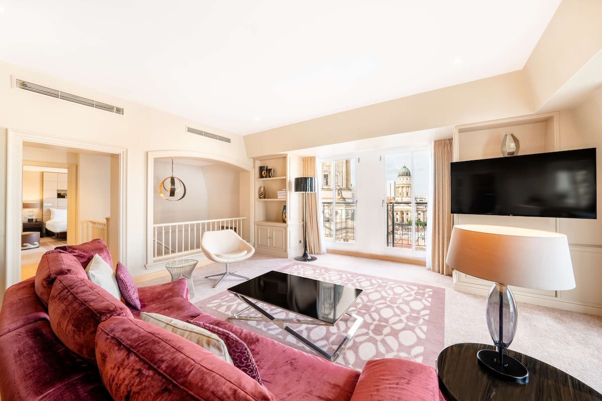 A spacious living room with a large flat-screen TV, a modern sofa, a coffee table, and a floor lamp.