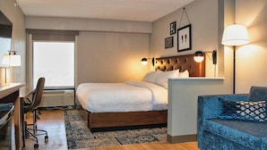 Une chambre d’hôtel équipée d’un lit, d’un bureau, d’une chaise, d’un canapé et de deux lampes fixées au mur.