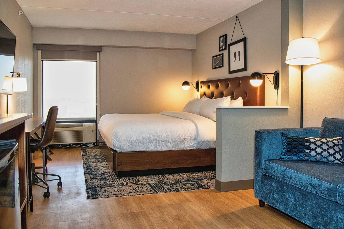 Een hotelkamer met een bed, een bureau, een stoel, een bank en twee wandlampen.