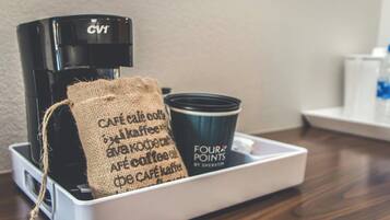 A coffee maker, a burlap sack, and a cup on a tray.