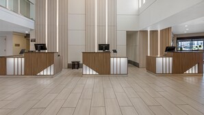 A spacious lobby with three reception desks, a high ceiling, and a modern design.