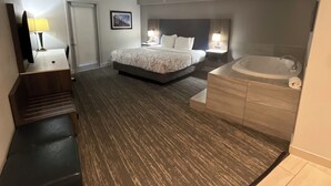 A hotel room with a bed, a desk, a chair, a desk lamp, a wall-mounted TV, a framed picture, a bathroom with a bathtub, and a shower.
