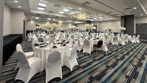 A conference room with round tables, white chairs, and floral centerpieces.
