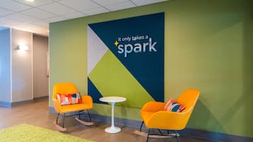 A modern lobby with two rocking chairs, a small round table, and a wall with a motivational quote.