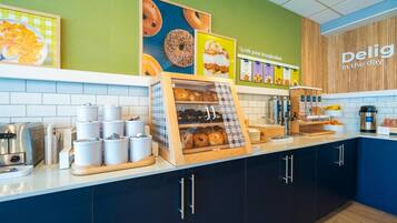 A bakery counter with a display case, coffee machine, and various bakery items.