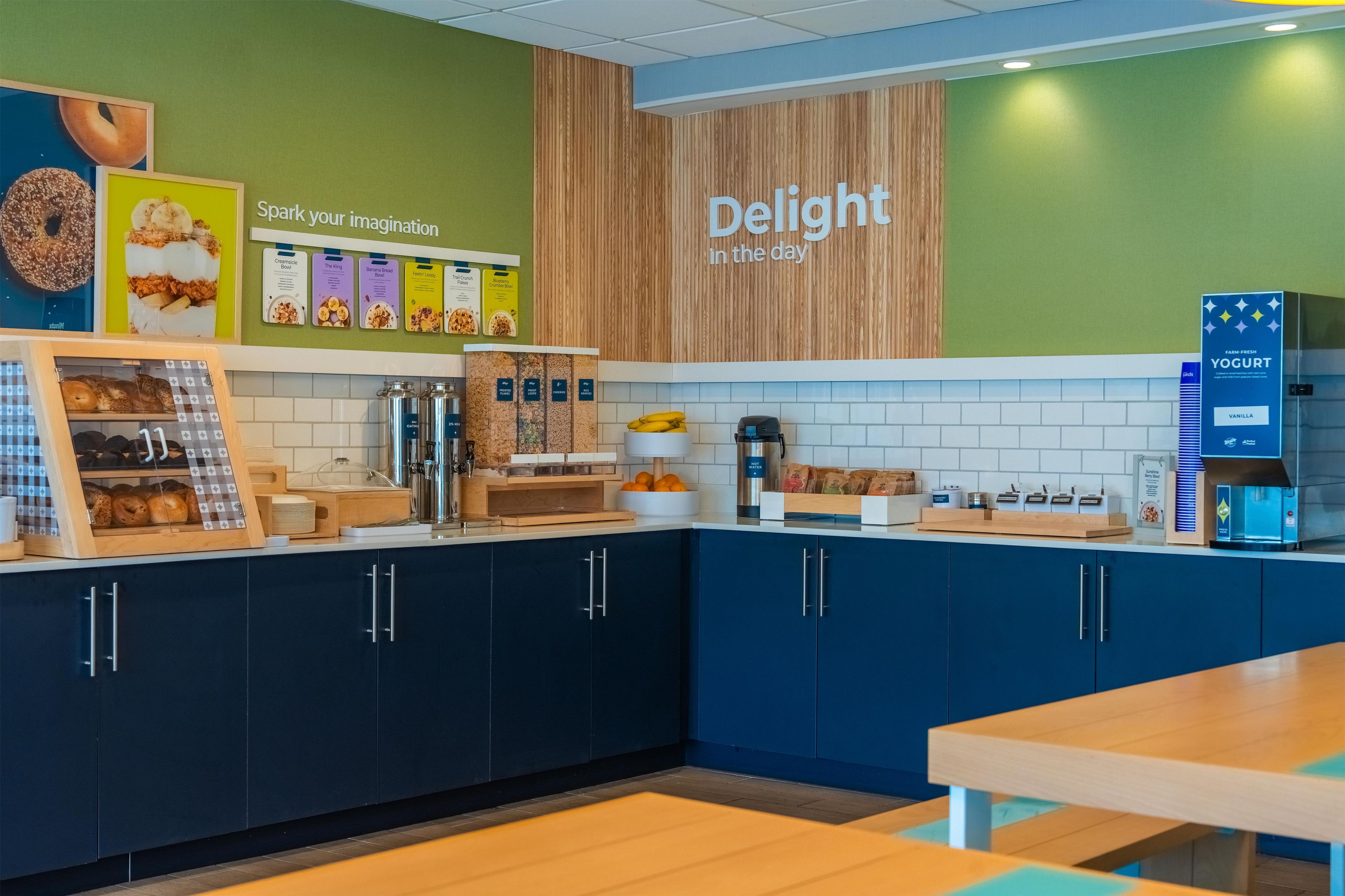 A modern café interior with a counter displaying various food items and a wall with a 'Delight in the day' sign.