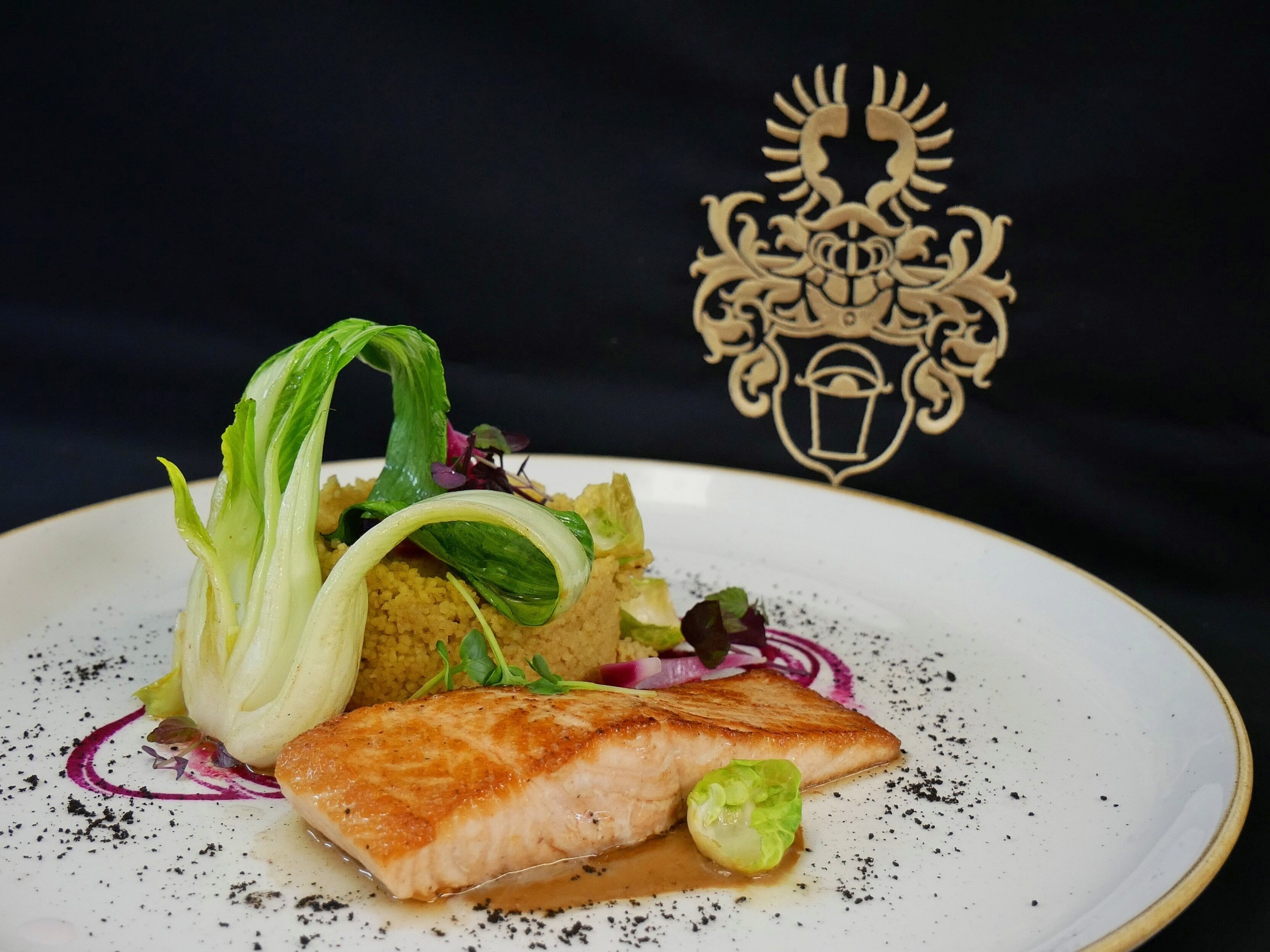 Ein Teller mit gegrilltem Fisch, Gemüse und Getreide.