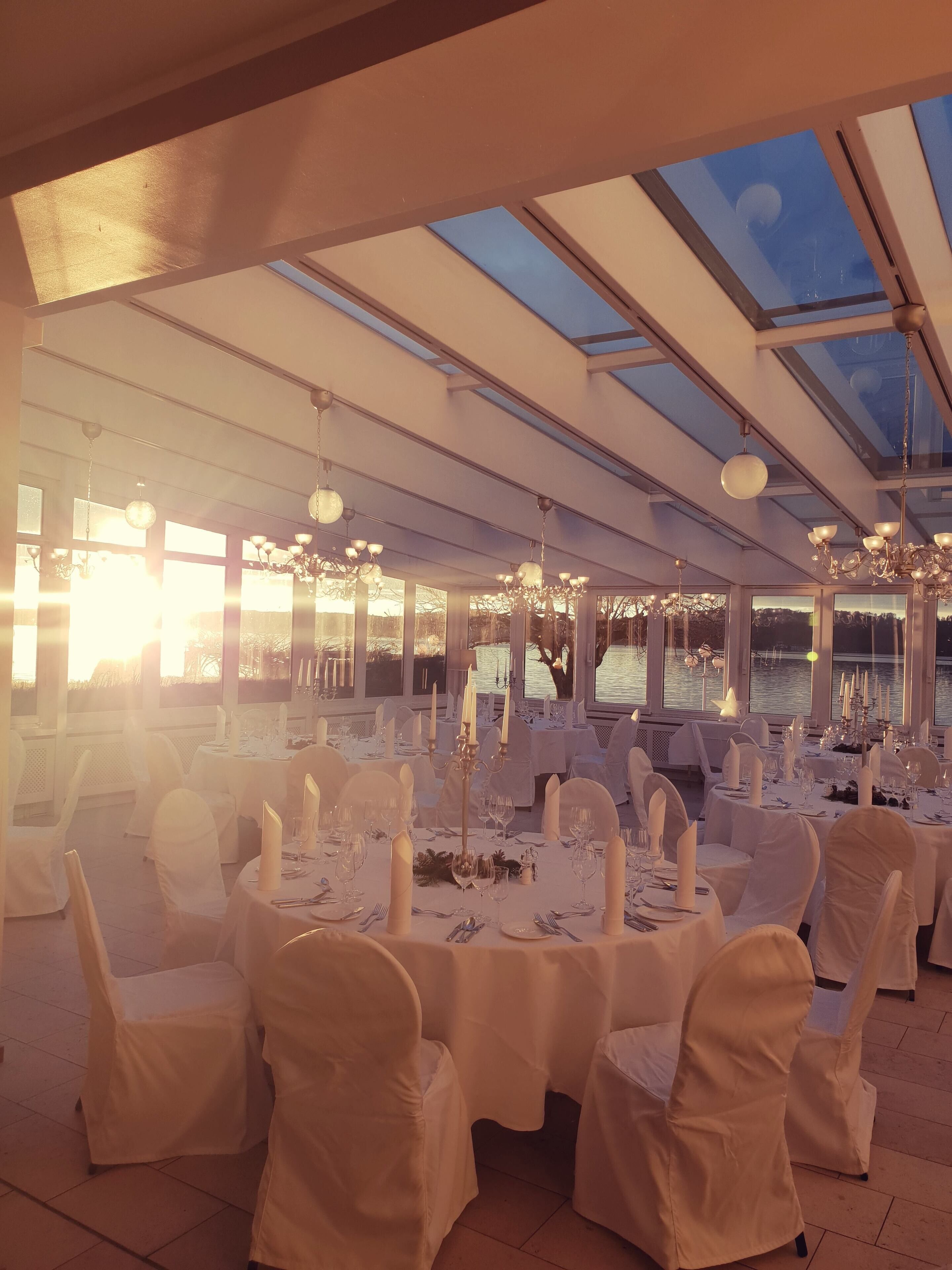 A formal dining area with round tables, white tablecloths, and candle centerpieces.
