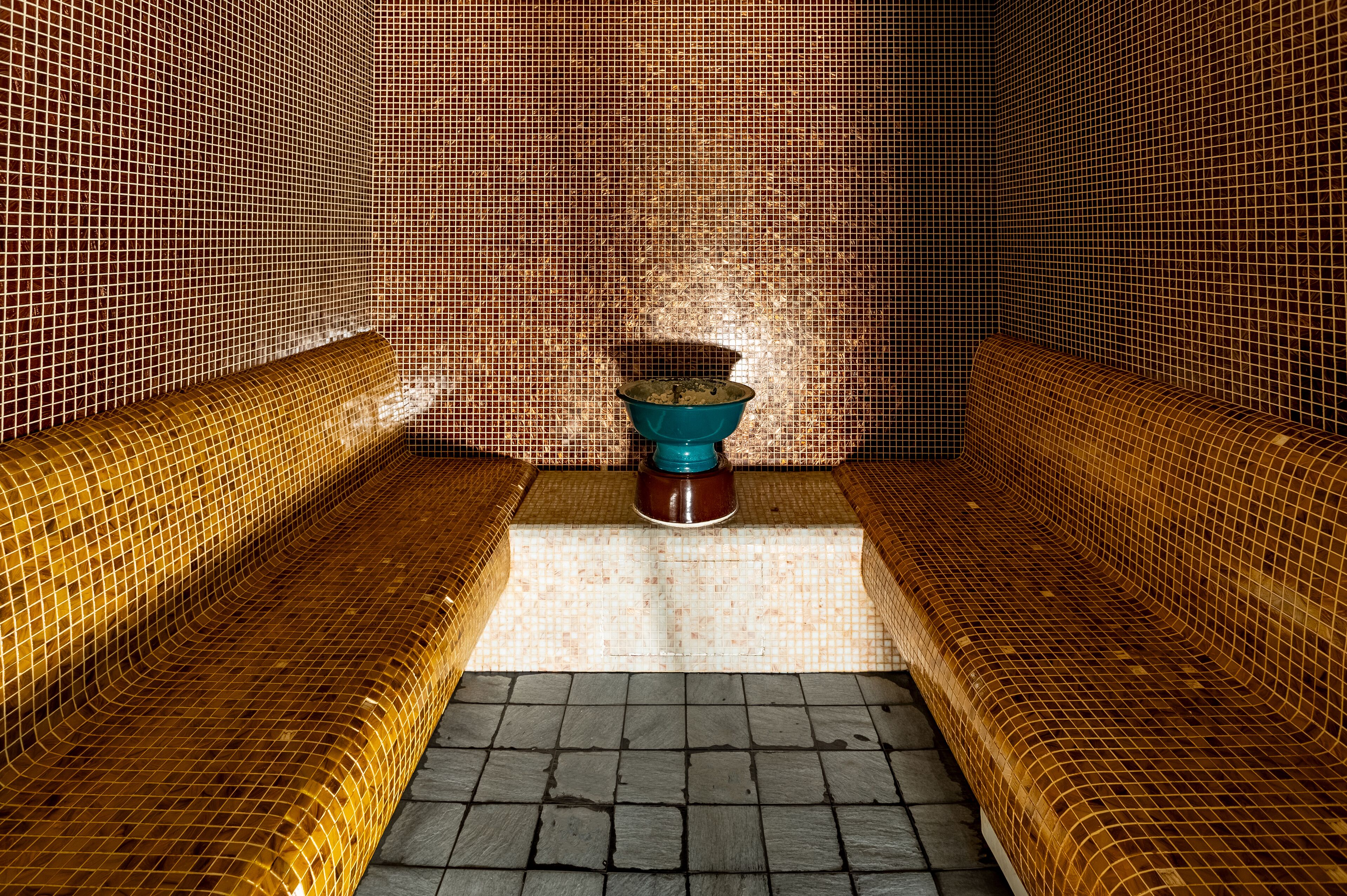 A bathroom with a tiled floor, a sink, and a shower area.