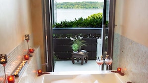 Un espacio de spa con bañera, velas y vistas a un lago.