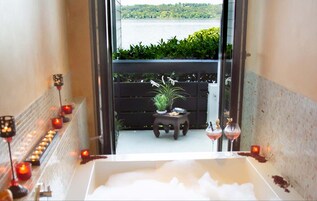 Área de spa com banheira, velas e vista para um lago.