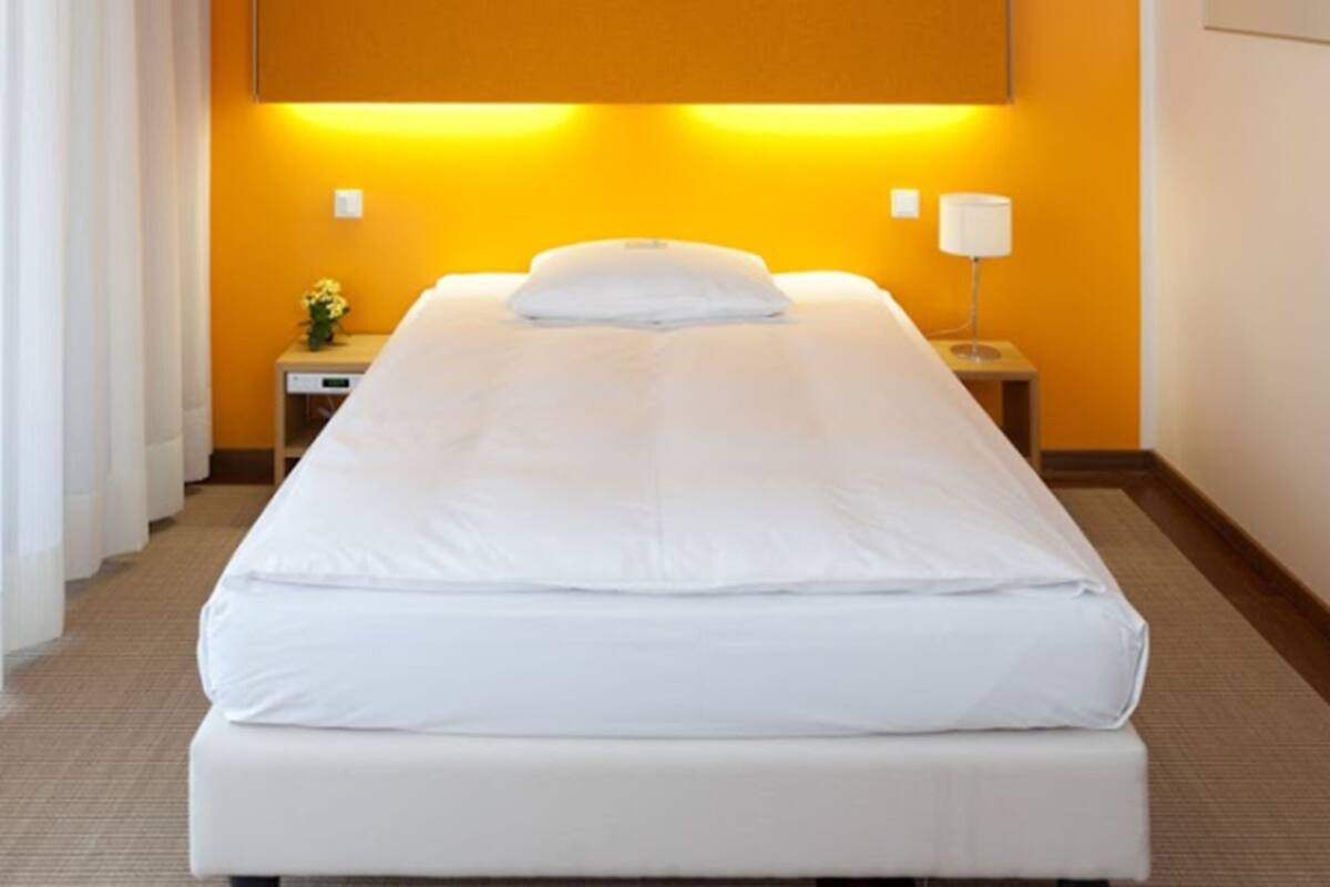 A hotel room with a large bed, a nightstand with a lamp, and a painting on the wall.