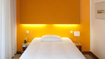 Habitació d'hotel amb un llit gran, una tauleta de nit amb una làmpada i un quadre a la paret.