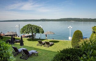 Área externa à beira do lago com cadeiras de descanso, guarda-sóis e um gazebo.