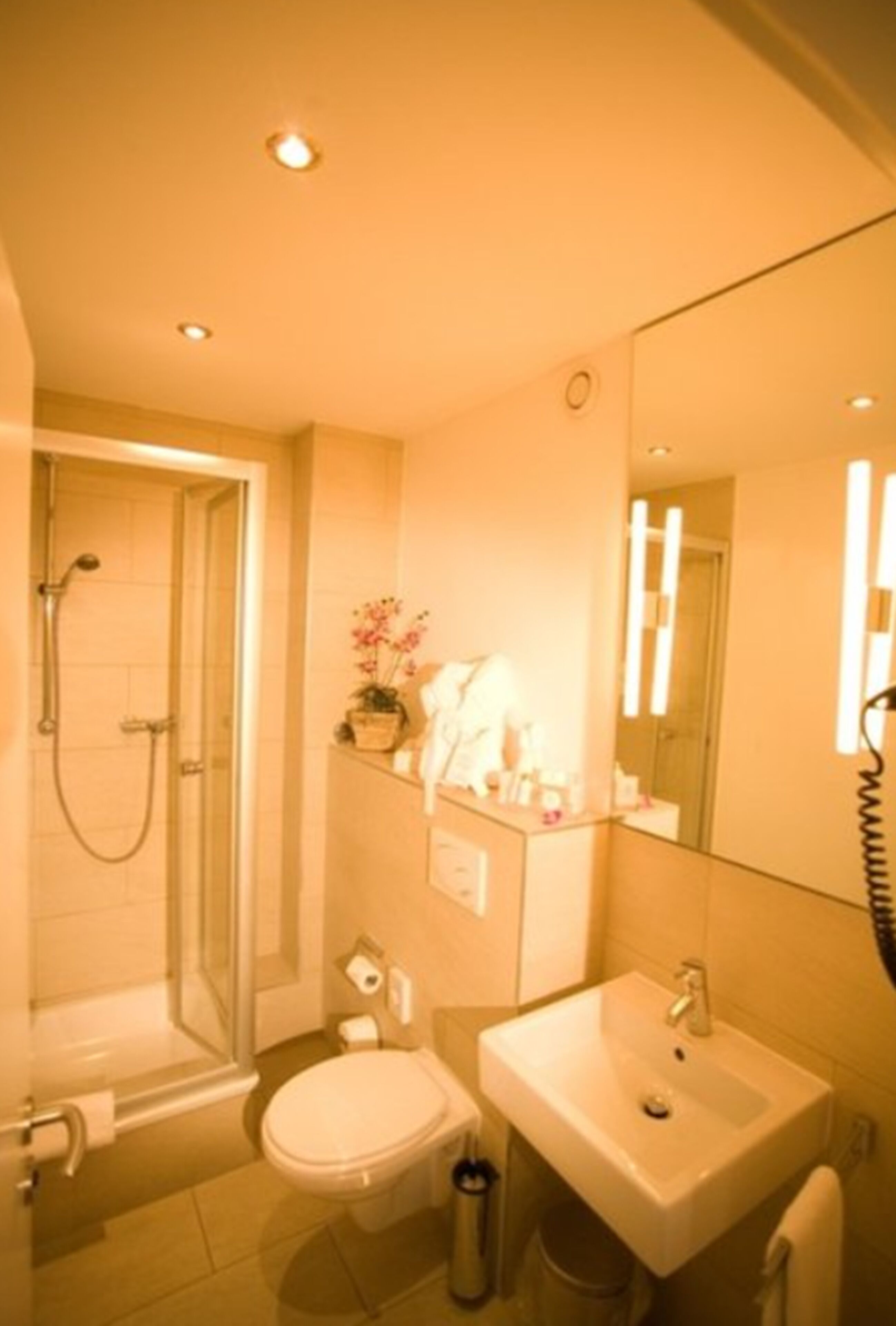 A modern bathroom with a shower, toilet, sink, and a large mirror.