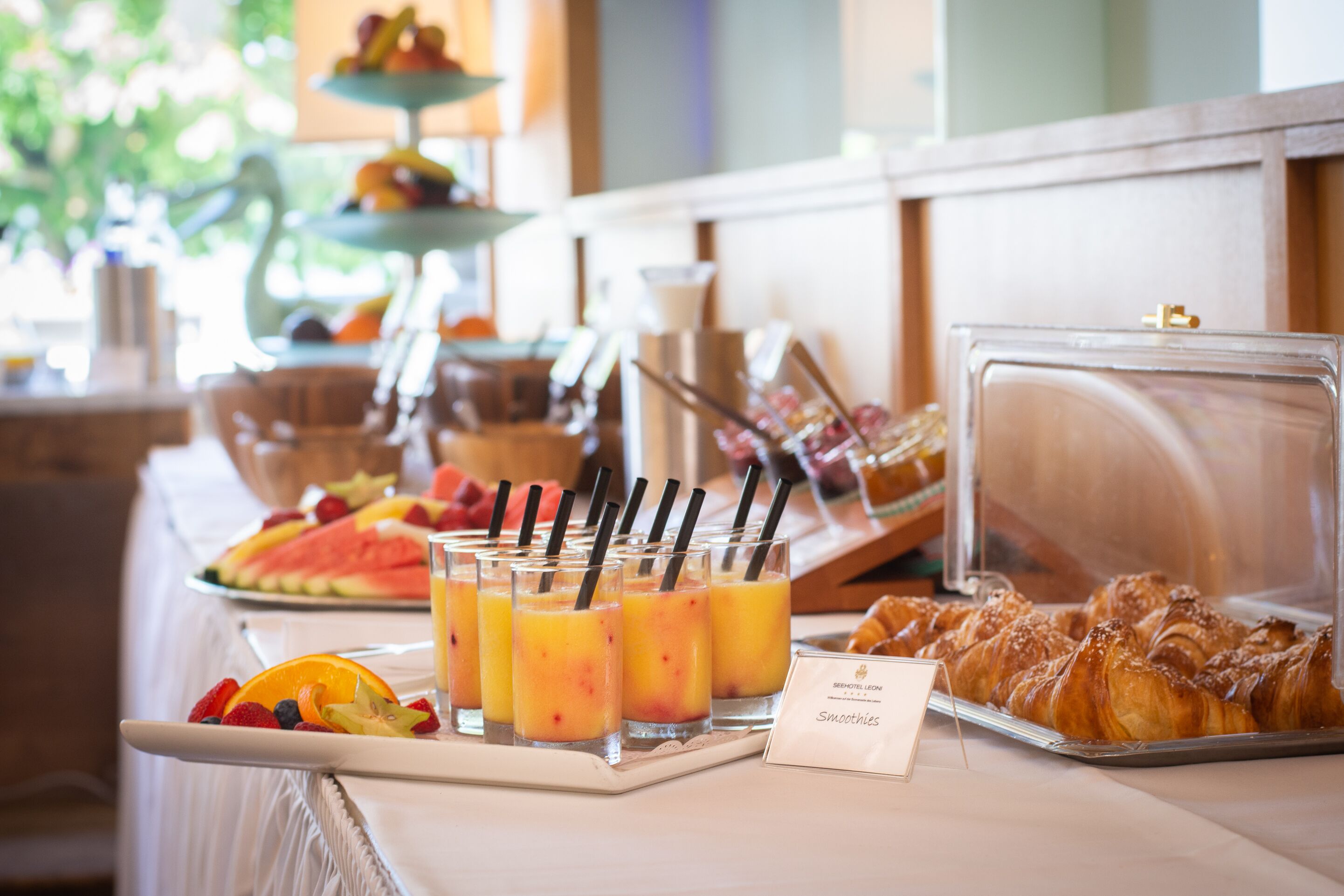 Un buffet de petit-déjeuner comprenant des fruits, des smoothies et des viennoiseries.
