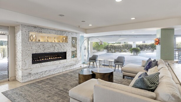 A modern living room with a fireplace, comfortable seating, and a view of the outdoors. - Belamar Hotel Manhattan Beach, Tapestry Collection by Hilton (Manhattan Beach)