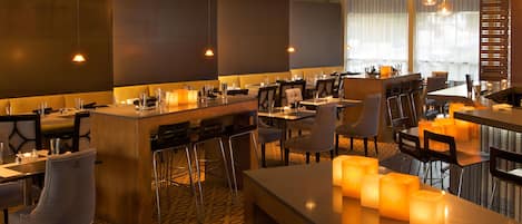 A modern hotel lobby with a bar area, seating arrangements, and a patterned floor.