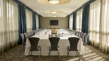 A conference room with a long table, chairs, and a television screen.