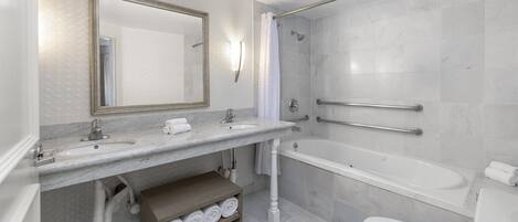 Moderni kylpyhuone, jossa on suuri peili, kaksi pesuallasta, kylpyamme ja wc.