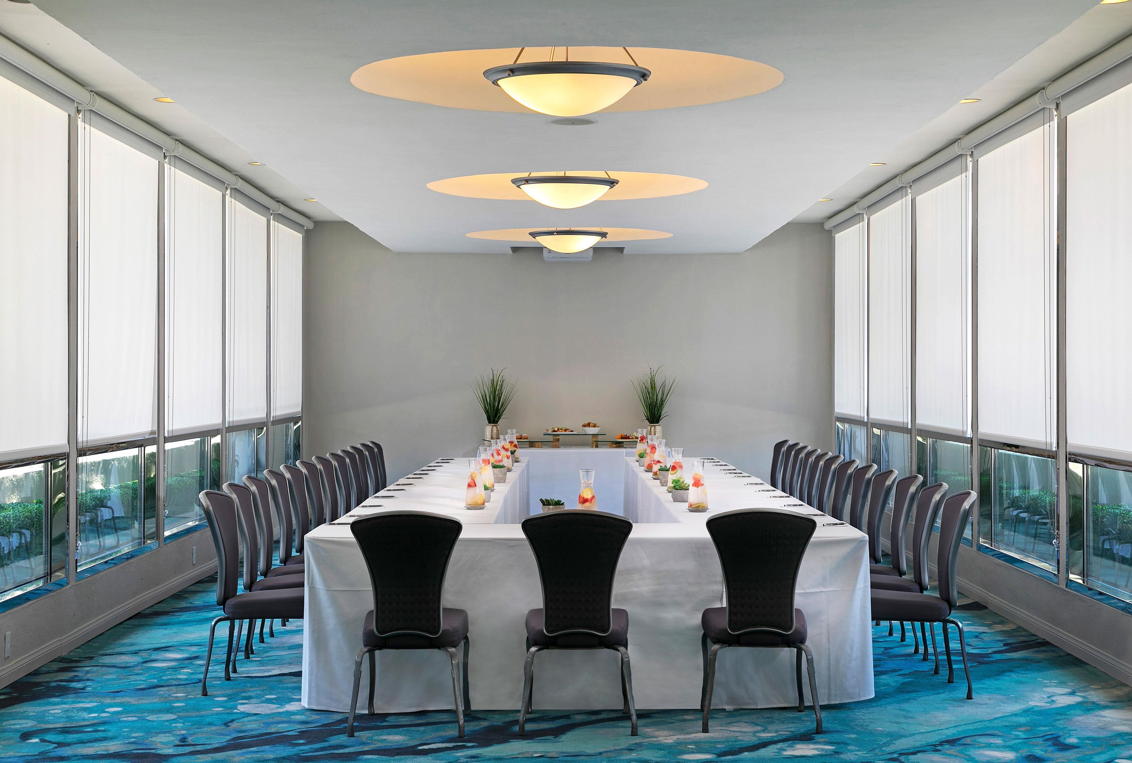 A conference room with a long table, chairs, and large windows.