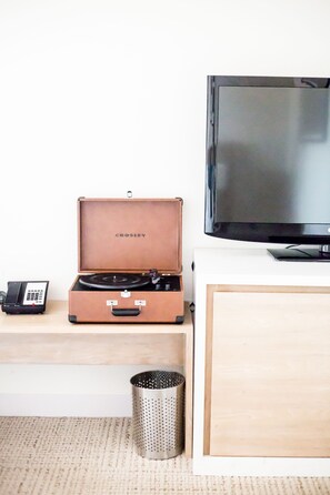 Una stanza con televisore, una valigia Crosley, telefono e un contenitore metallico.