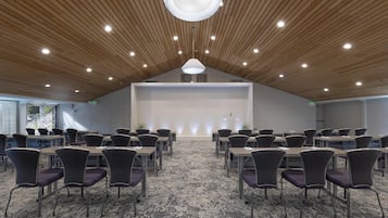 A conference room with a high ceiling, wooden slats, and a central stage.